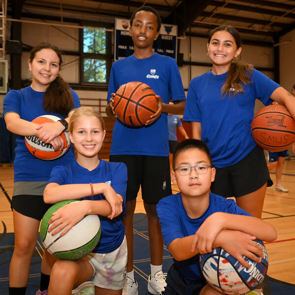 Group of five players taking a staged photo holding Basketballs 