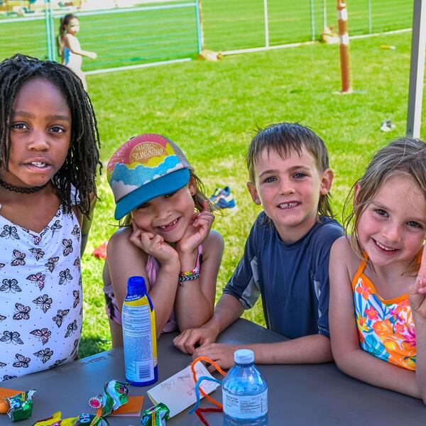 Four day campers smiling at the camera with a watertight happening around them