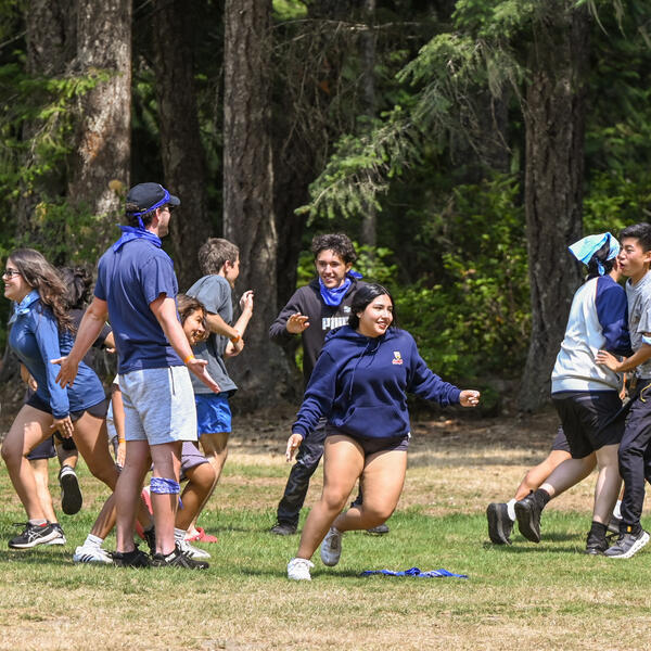 Campers playing a game of tag with SMUS Camps staff on a field at Camp Barnard 