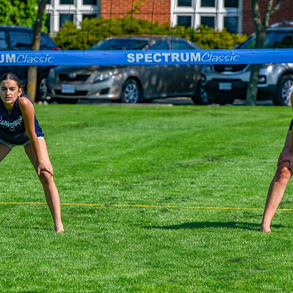 Two female campers on volleyball court guarding ready to block the ball
