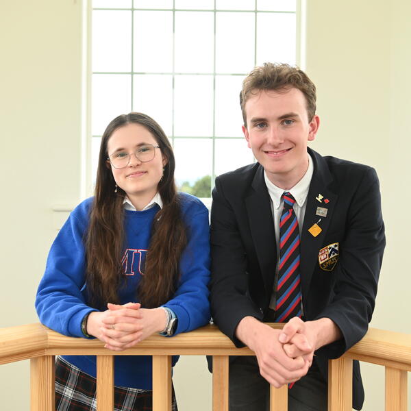 A photo of head prefects Chelsea Lee and Will Cuddihy leaning over a banister up in the sun lit bell tower of the SMUS School House Building. 