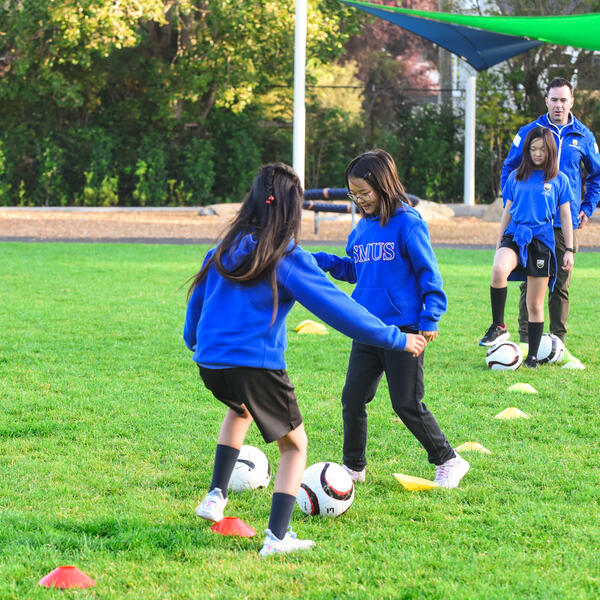 Junior School students practice soccer on the field 