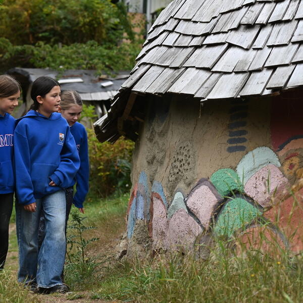 Grade 6 students walk up a path admiring the Ecovillage Dragon Wall with artwork from generations of SMUS students