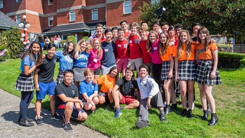 Large group of boarding students in their house shirts in front of houses