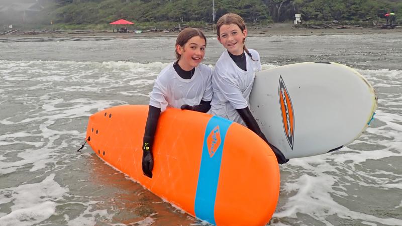 Two students pose with surfboards in Tofino, BC