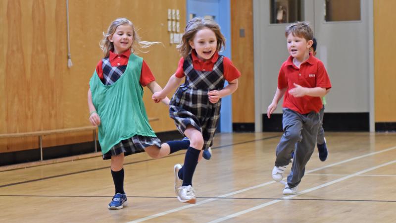 A trio of Kindergarten students run around in the Junior School gymnasium.