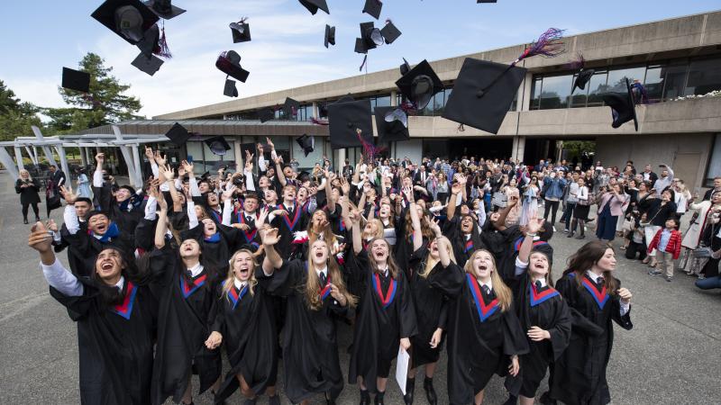 Grade 12 students throw their caps in the air to celebrate graduation.