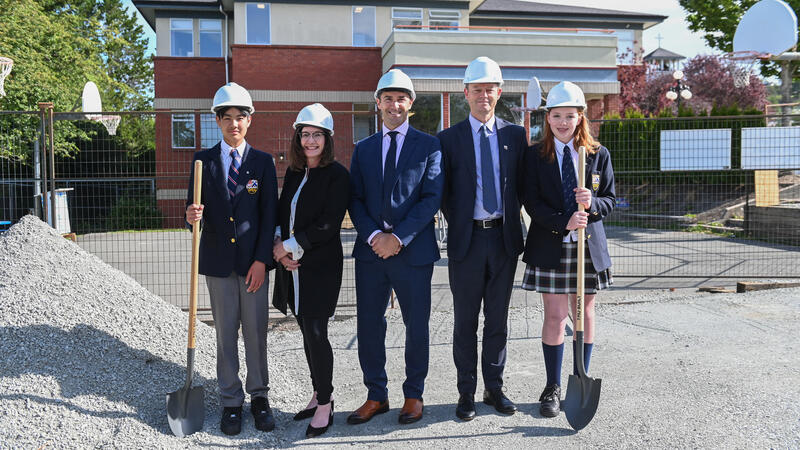 A group of SMUS representatives including two students, Chair of the Board of Governors, Acting Head of School and Director of Middle School stand with hard hands and shovels at the ground breaking for the Middle School Project.
