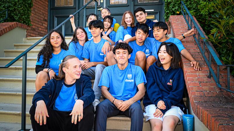Group of overnight campers sitting on stairs into SMUS. Smiling and having fun chatting to each other