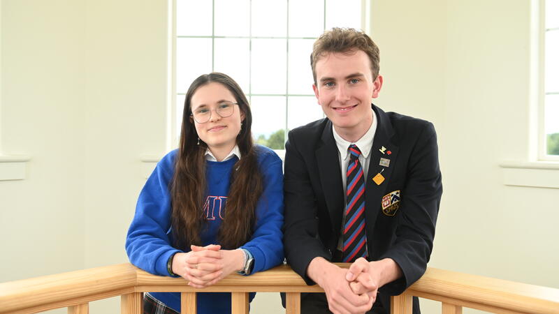 A photo of head prefects Chelsea Lee and Will Cuddihy leaning over a banister up in the sun lit bell tower of the SMUS School House Building. 