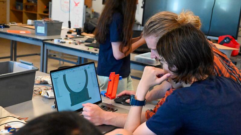 Camper and staff member working on Engineering problem togther
