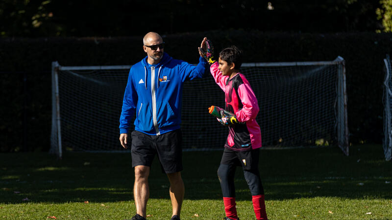 SMUS Soccer coach Mike Danskin gives a high five to a middle school soccer team goalie on the field
