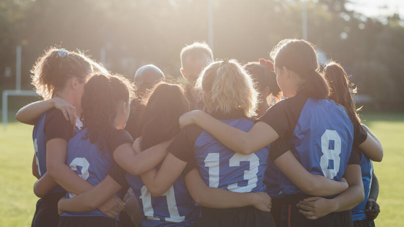 SMUS Rugby Team embrace in a team huddle as the sun beams down. 
