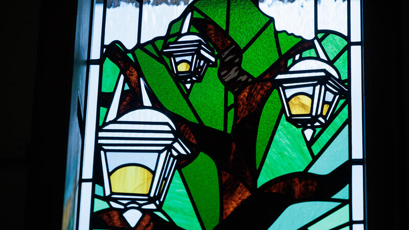 A close up of a student-designed stained glass window showing three lanterns in a tree. 