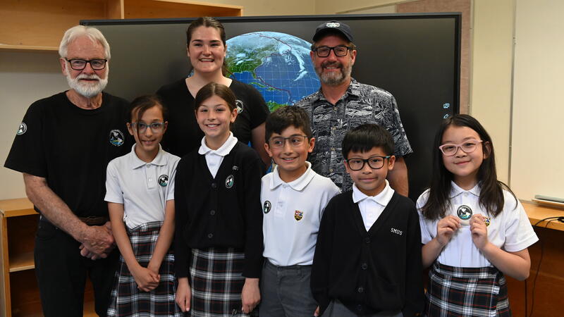 Grade 4 students pose with members of the visiting One Ocean crew