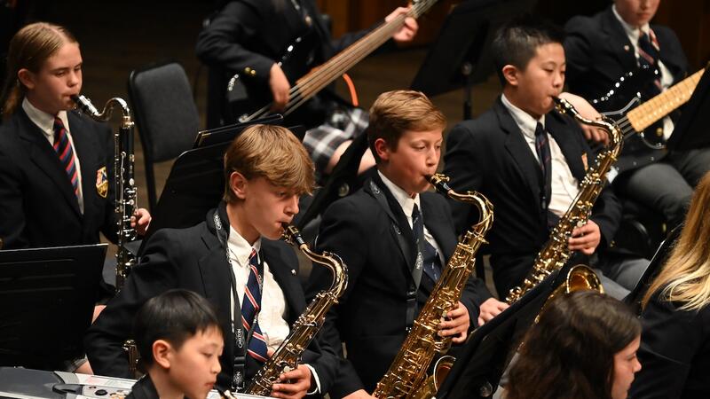 Saxophone players in the Middle School band concentrate while performing on stage. 