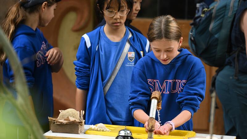 Middle School students use a foot pump sink to wash their hands before snack time.