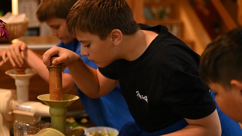 Middle School students use a hand juicer.