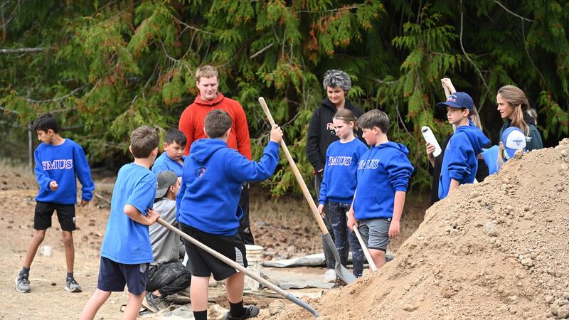 Grade 6 students dig in with shovels to a pile of dirt as the prepare to make cob walls.