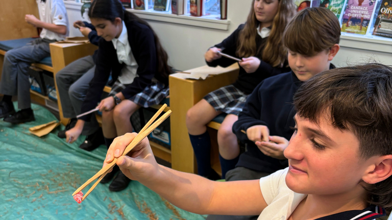 A student using chopsticks carved from cedar