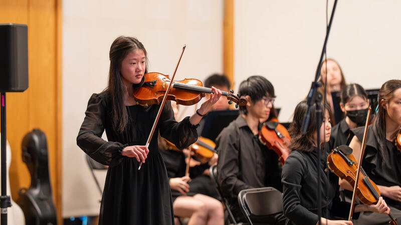 Michaela Yee stands for a violin solo during a performance.