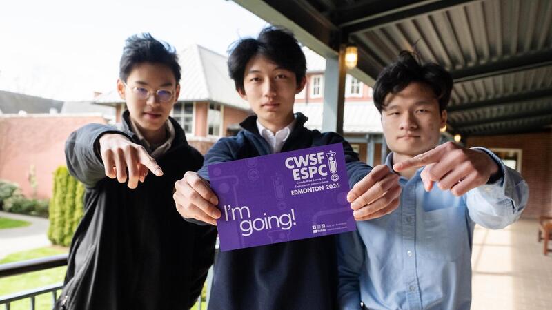 Senior School students George, Ruibo and Alvin pose with a postcard that says they are going to the national science fair.