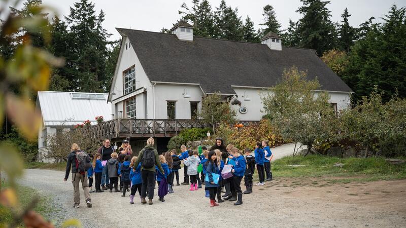 Students arrive at the Sea Cider winery and walk down the path towards the main building.