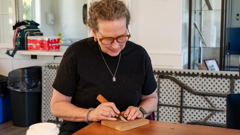 A staff member carves her cedar blog peacfully