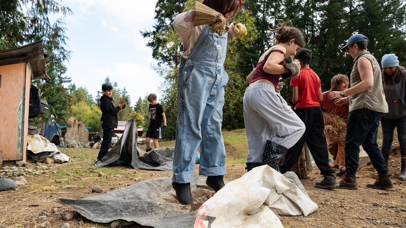 Students stomp on tarps breaking up large clumps of dirt to prepare for the clay mud wall. 
