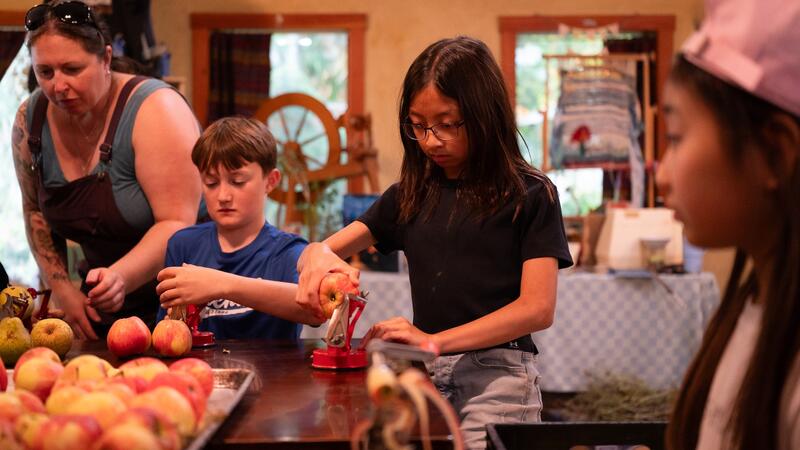 Students are hard at work around a big table coring and peeling apples.